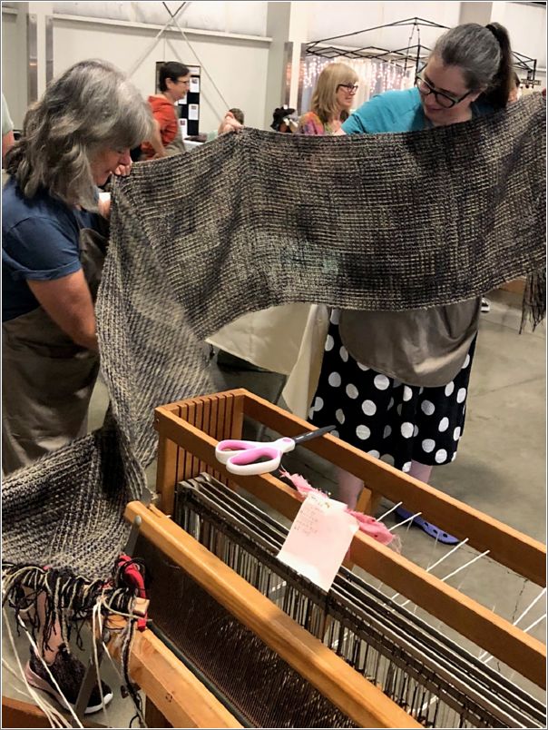 Team # 2s Kristy Hewitt inspects the shawl made of Border Leicester wool as it comes off of the loom. Photo: Aurora Colony Handspinners Guild.